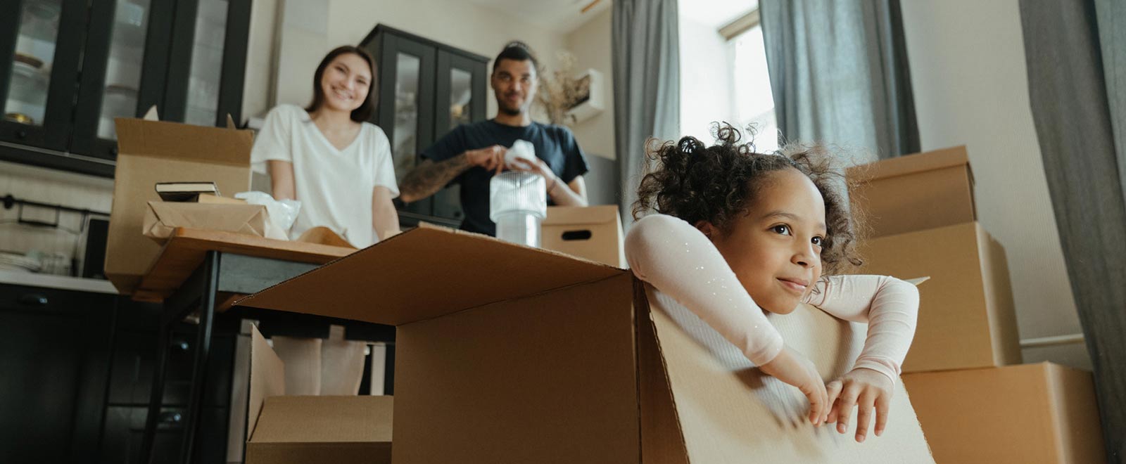 Parents and child unpacking boxes in new home.