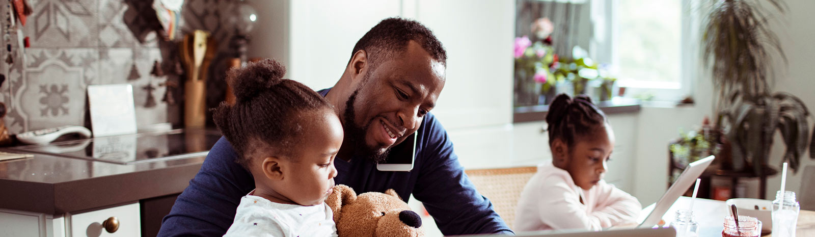 Dad with young twins talking on phone at home.